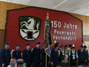 Mitglieder und Gäste vor dem Schriftzug zum 150-jährigen Bestehen der Feuerwehr Vachendorf