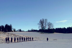 Böllerschützen stehen in einer Reihe auf einer verschneiten Wiese in Mühlbach.
