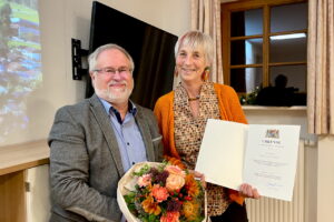 Rainer Schroll überreicht Marlies Kruse Blumen und eine Urkunde