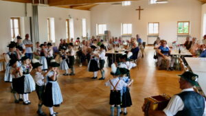 Kinder in Tracht tanzen vor den Gästen im Saal