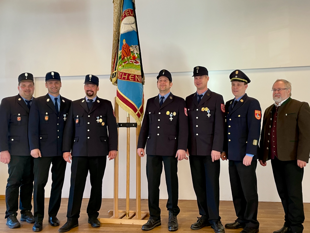 Gruppe geehrter Feuerwehrmänner vor der Fahne