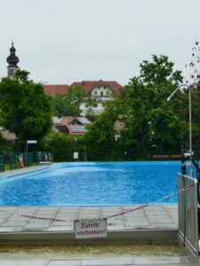 Das gefüllte Vachendorfer Schwimmbad mit Kirchturm im Hintergrund