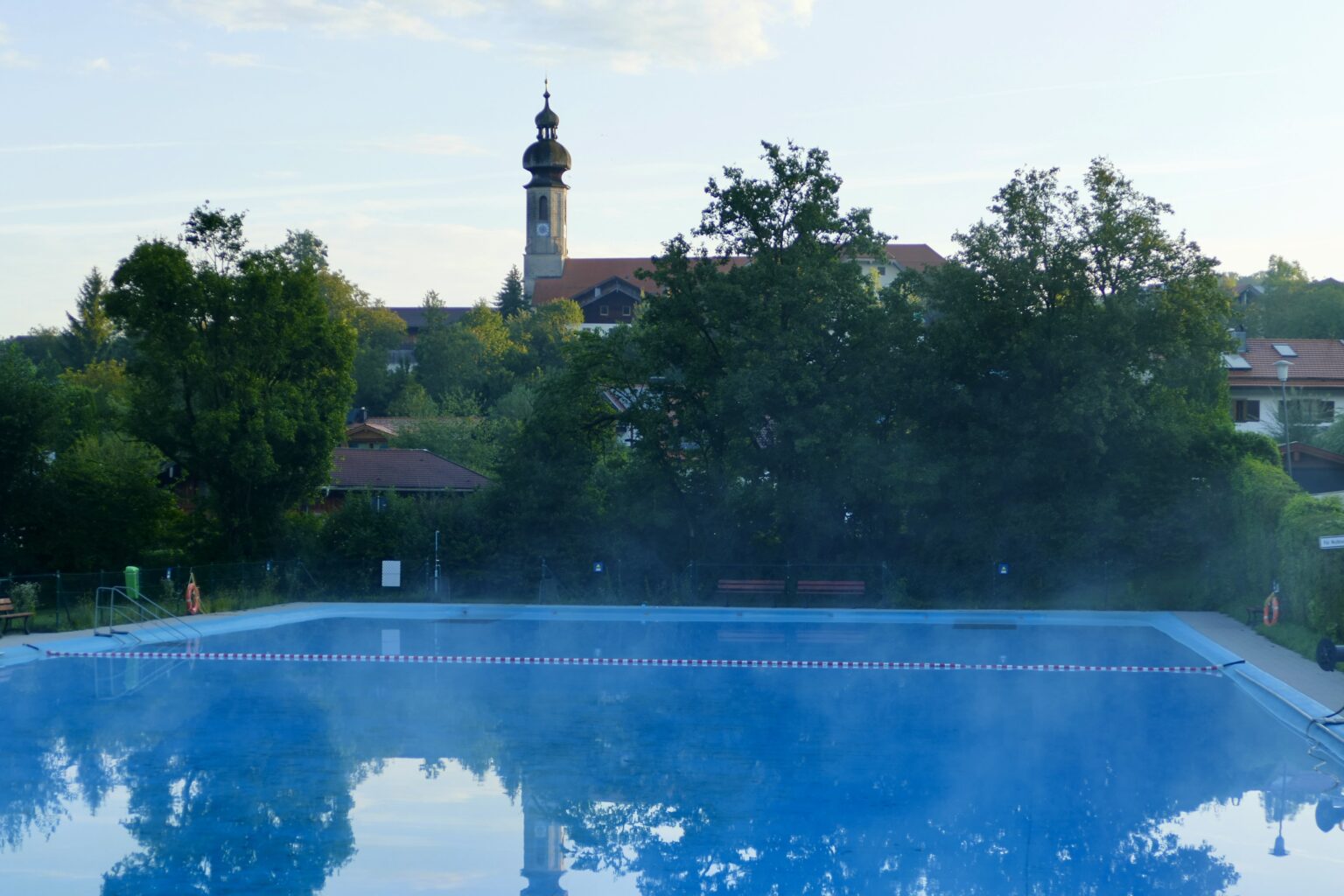 Blick über das Vachendorfer Schwimmbad zum Kirchturm