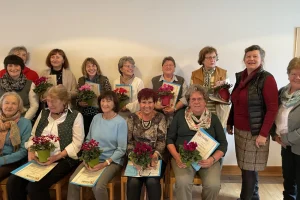 Mitglieder der Frauengemeinschaft Vachendorf bei einer Ehrung mit Blumen und Urkunden.