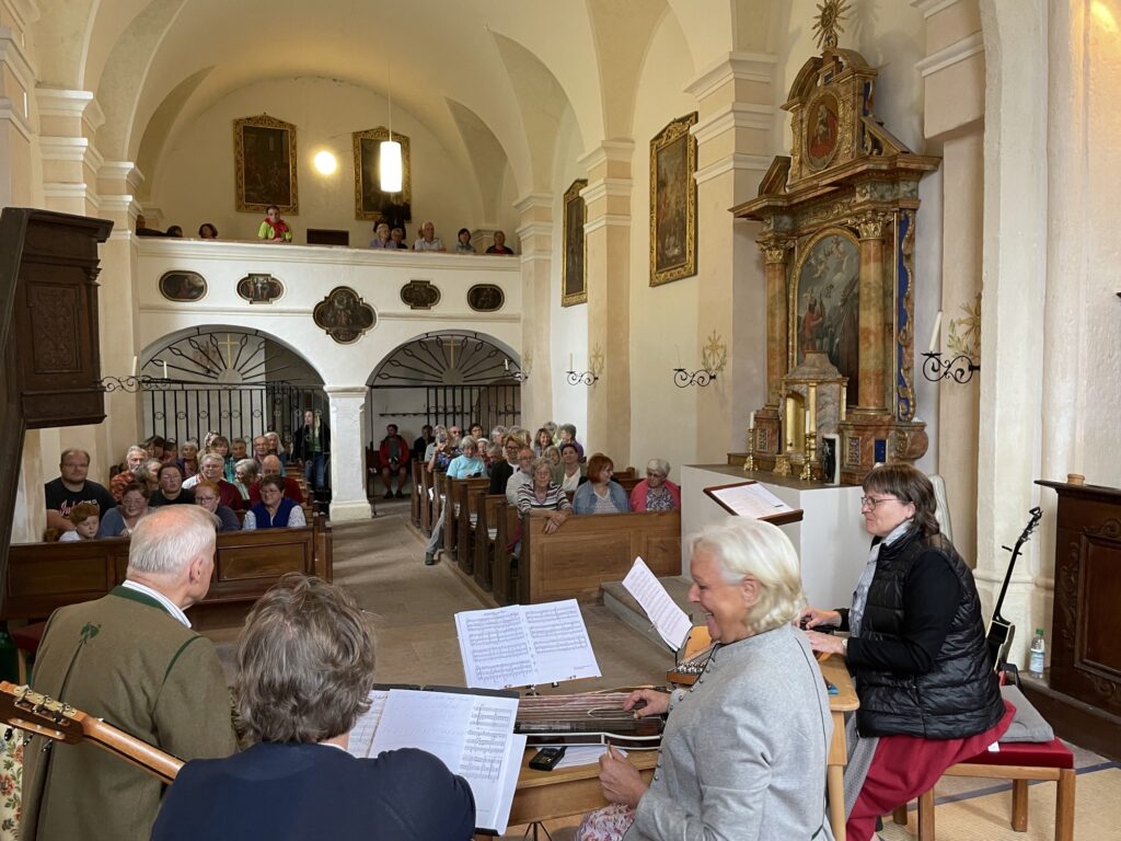 Die Vachendorfer Zithermusi spielt vor dem voll besetzten Kirchenschiff.
