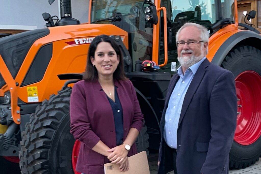 Sabrina Stutz und Bürgermeister Rainer Schroll stehen vor dem orangefarbenen Fendt-Schlepper.