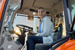 Gemeinderätin Marlies Kruse sitzt lachend in der Fahrerkabine des neuen Bauhofschleppers.