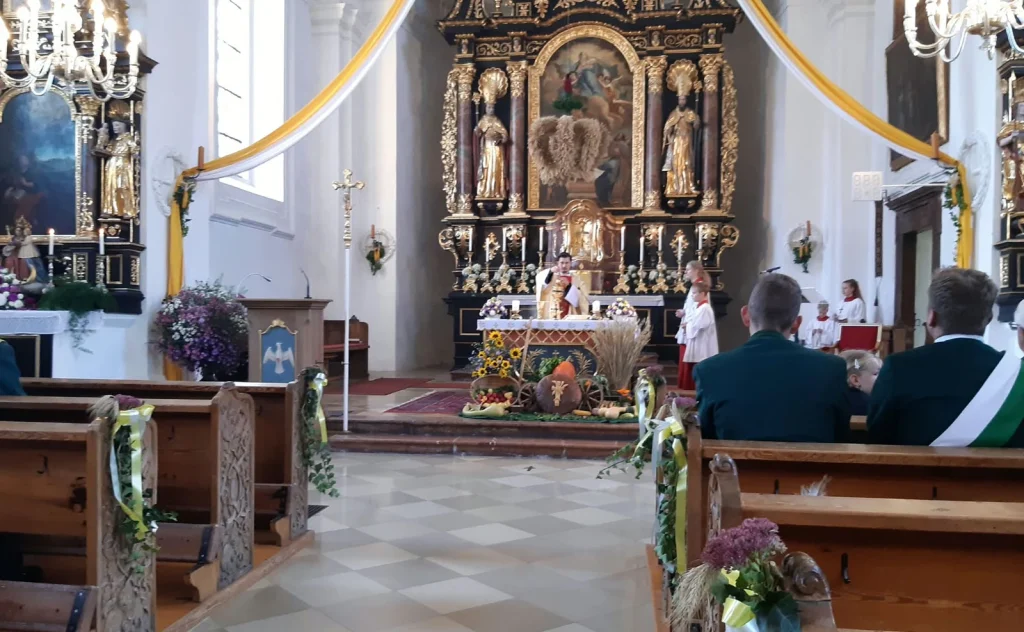 Pater Andrei Mirt am Altar mit Erntekrone, Brotlaib und Erntegaben in Mariä Himmelfahrt Vachendorf.