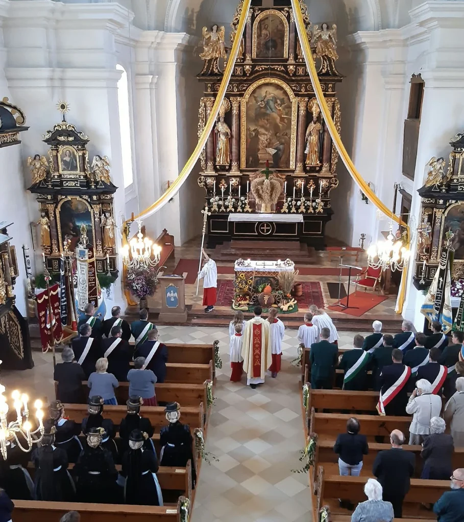 Blick von der Empore auf Pfarrgemeinde, Altardienst und Fahnenabordnungen beim Erntedankgottesdienst in Vachendorf.