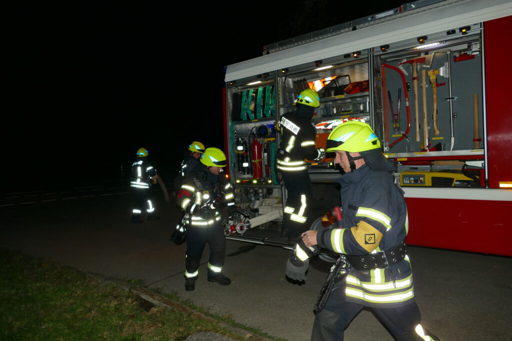 Feuerwehrmitglieder entnehmen bei der Leistungsprüfung Ausrüstung aus dem geöffneten Löschfahrzeug.