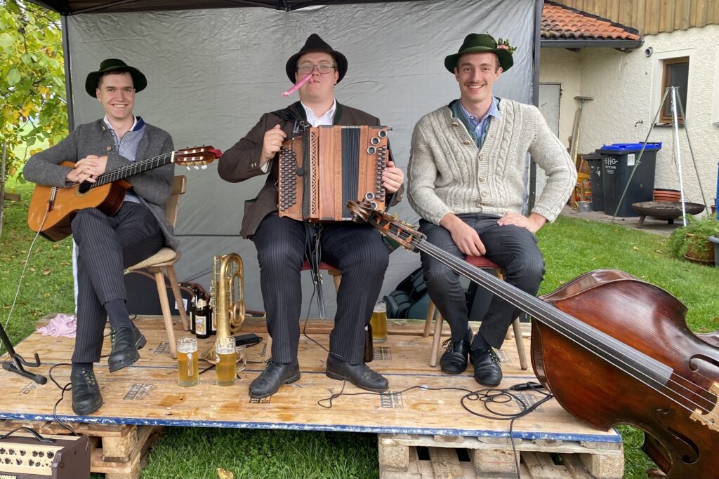 Drei Musiker mit Gitarre, Ziach und Kontrabass auf einer kleinen überdachten Bühne.
