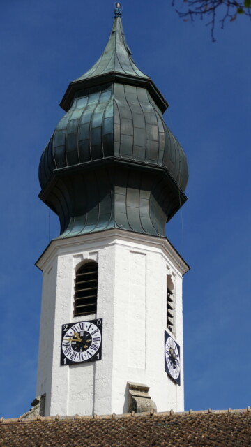 Der schöne Zwiebelturm im Frühlicht. Er wurde nach dem Vorbild Vachendorf und Haslach (dortiger Baumeister Lorenzo Sciasca) in der Barockzeit gestaltet. Die "Schnecken" an den unteren Ecken nennt der Denkmalpfleger fachlich korrekt "Voluten". Überragt das Dorf seit Jahrhunderten, der Zwiebelturm im Frühlicht