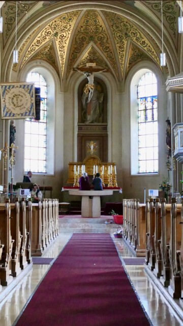 Der Blick durch das Hauptschiff von St. Ägidius in Bergen führt auf den goldenen Tabernakel und das Hochaltarbild des Kirchenpatrons zu, überragt vom Kreuz und umfangen von einem leuchtenden Rankenhimmel – ein Raum, der sich vom Gebet zum himmlischen Lob erhebt. Bergen st aegidius gesamteindruck