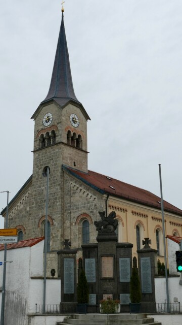 Die Pfarrkirche St. Maximilian in Grabenstätt erhebt sich mit markanter Turmhaube und neoromanischen Rundbogenfenstern als stolzes Wahrzeichen der Gemeinde St. Maximilian mit Kriegerdenkmal