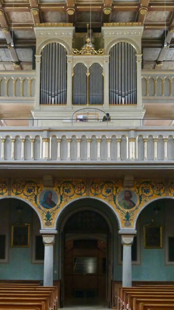 Die Orgelempore präsentiert sich mit klassizistischer Pfeifenfront, goldverzierter Balustrade und einem reich ornamental bemalten, fast byzantinisch anmutenden  Arkadenvorbau. Grabenstaett st maximilian gesamteindruck