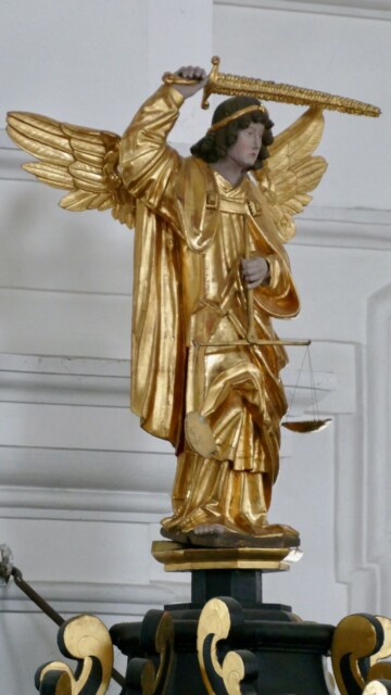 Auf dem Kanzel-Baldachin steht der Hl. Michael mit Flammenschwert und Seelenwaage wie ein Chef der Figurenschar, die der Bildhauer Georg Pämer aus Traunstein um 1685 schuf. Der Erzengel Michael als Seelenwäger